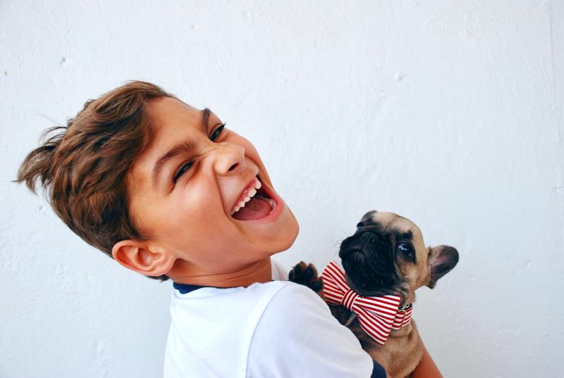 young boy smiling and holding puppy