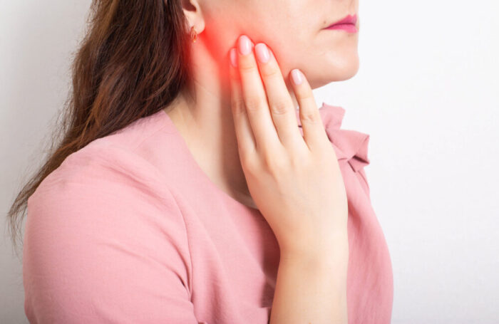 woman holding her face wondering what helps TMJ pain